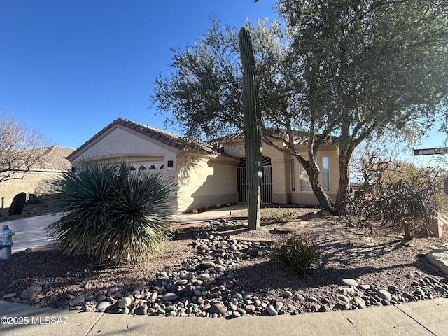 view of side of home with a tiled roof, an attached garage, and stucco siding