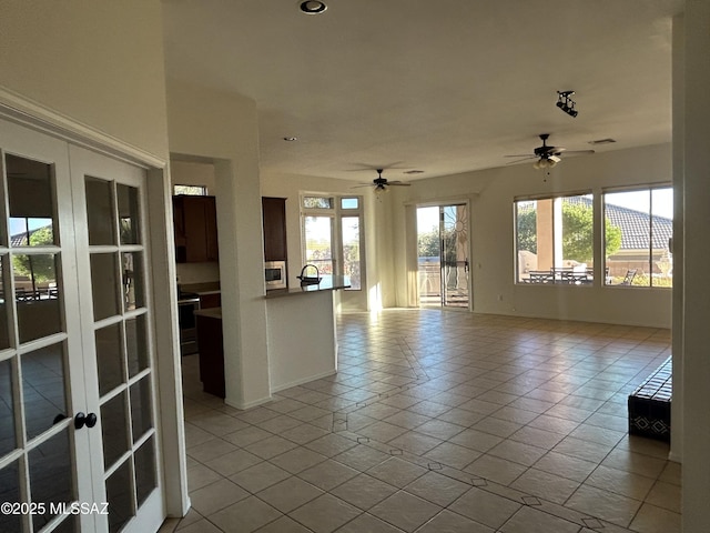 tiled empty room with french doors and a ceiling fan