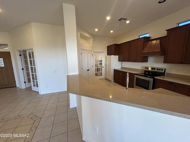 kitchen featuring light stone counters, visible vents, stainless steel range with electric cooktop, custom exhaust hood, and white fridge with ice dispenser