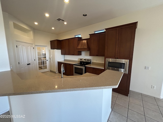 kitchen with light tile patterned flooring, a sink, light countertops, appliances with stainless steel finishes, and custom range hood