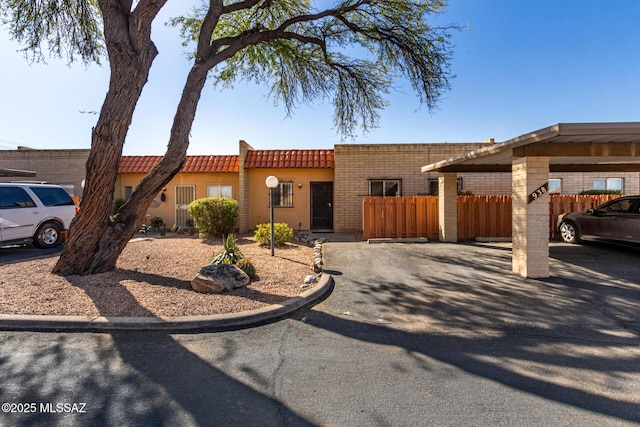 view of front of home with covered parking, a tile roof, and fence