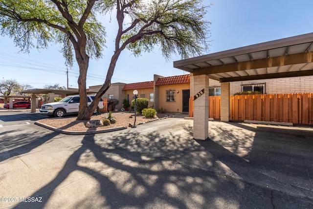 view of front of property with driveway, fence, and a tiled roof