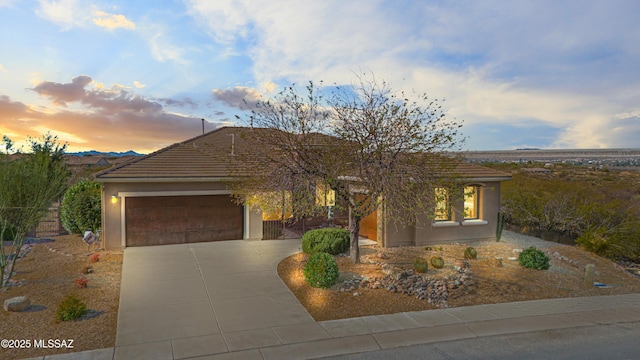 view of front of home with driveway, an attached garage, and stucco siding