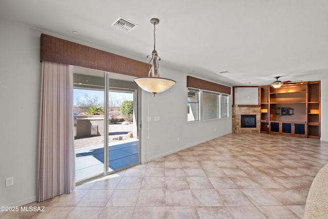 unfurnished living room featuring ceiling fan, visible vents, baseboards, and a stone fireplace