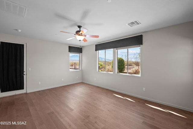 empty room with visible vents, baseboards, and wood finished floors