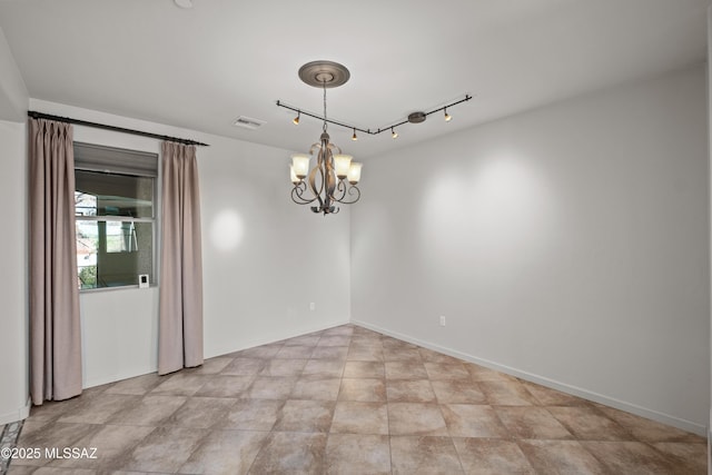 empty room with an inviting chandelier, baseboards, visible vents, and track lighting