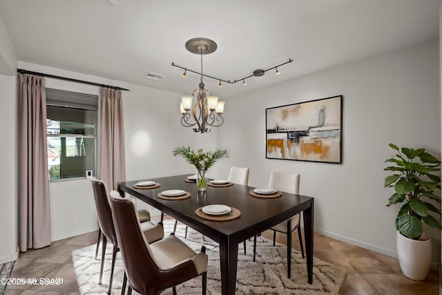 dining room featuring a chandelier, track lighting, visible vents, and baseboards