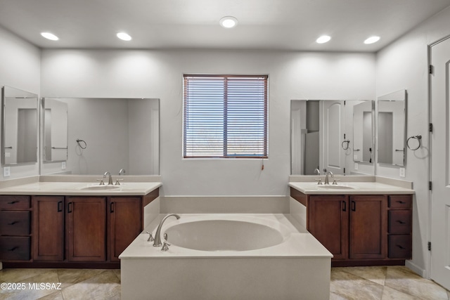 bathroom featuring recessed lighting, two vanities, a sink, and a bath