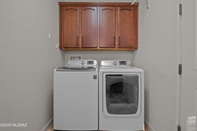 clothes washing area featuring independent washer and dryer, cabinet space, and baseboards