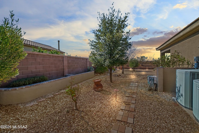 yard at dusk with cooling unit and fence