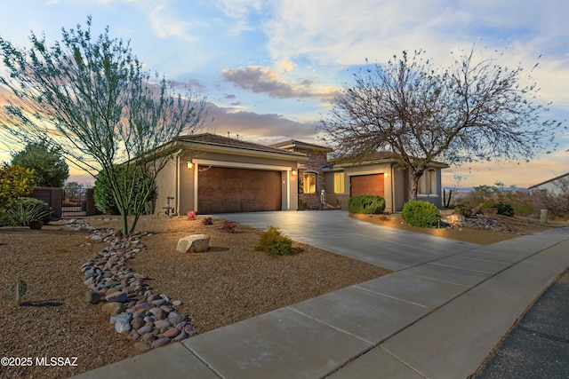 view of front of house with a garage, driveway, fence, and stucco siding