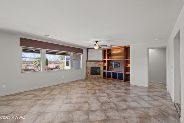 unfurnished living room featuring ceiling fan, visible vents, baseboards, and a glass covered fireplace