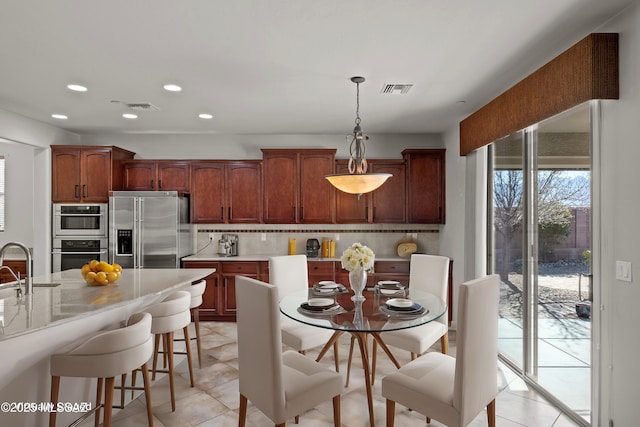 kitchen with stainless steel appliances, light countertops, visible vents, and backsplash