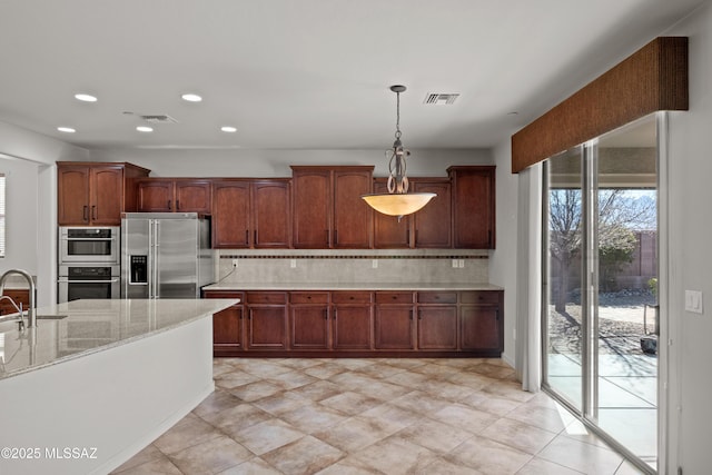 kitchen featuring appliances with stainless steel finishes, visible vents, a sink, and decorative backsplash