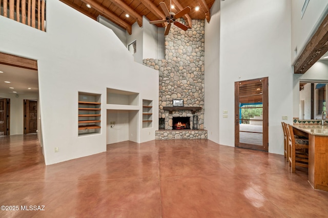 unfurnished living room with ceiling fan, a fireplace, wood ceiling, built in features, and finished concrete floors