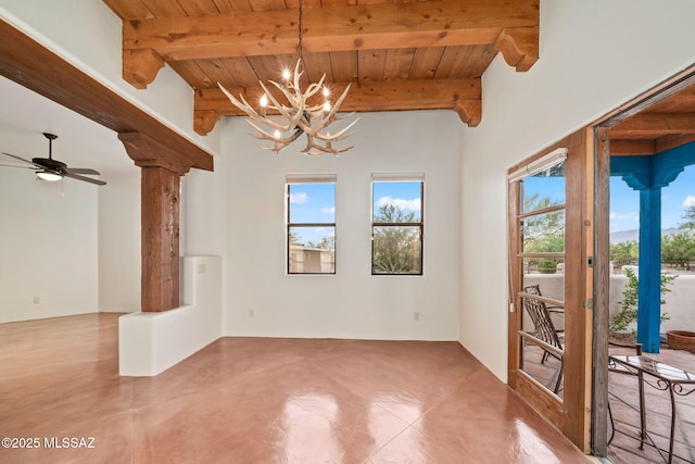 empty room with wooden ceiling, beamed ceiling, ornate columns, concrete floors, and ceiling fan with notable chandelier