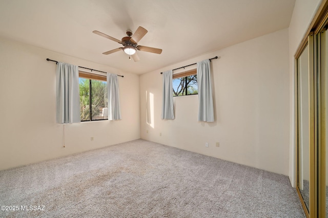 spare room featuring carpet floors, a healthy amount of sunlight, and a ceiling fan