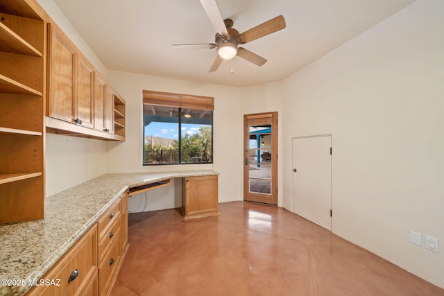 unfurnished office featuring concrete flooring, built in study area, and a ceiling fan