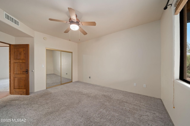 unfurnished bedroom featuring carpet floors, ceiling fan, visible vents, and a closet