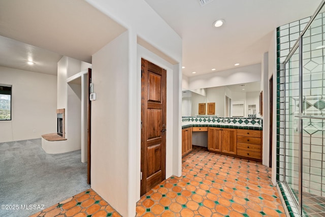 bathroom featuring a fireplace, recessed lighting, decorative backsplash, a shower stall, and vanity