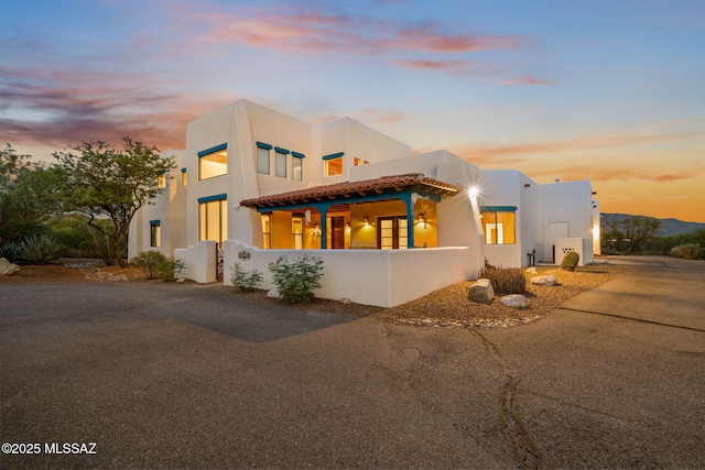 pueblo revival-style home featuring driveway and stucco siding