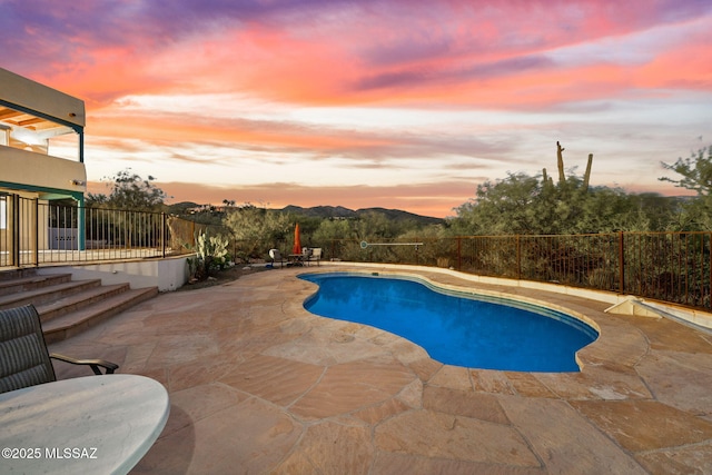 pool at dusk featuring fence private yard, a fenced in pool, and a patio