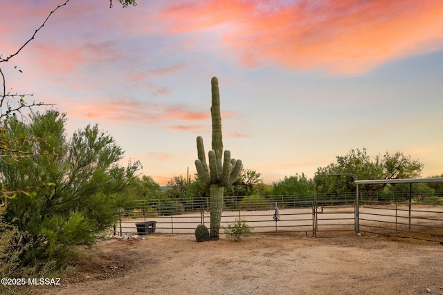 yard at dusk featuring an outbuilding, a rural view, and an enclosed area