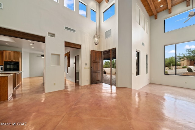 unfurnished living room featuring beam ceiling, visible vents, finished concrete flooring, and ceiling fan with notable chandelier