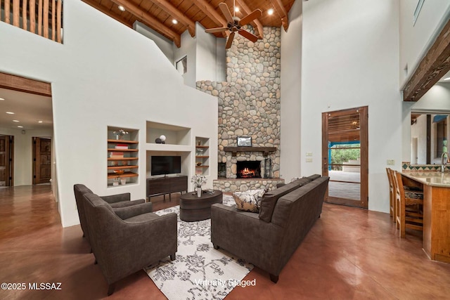 living room featuring finished concrete flooring, wood ceiling, built in features, and a stone fireplace