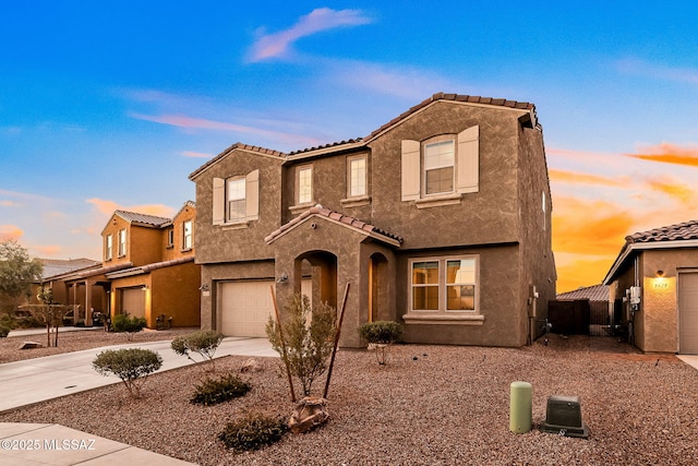 view of front of property with a garage, driveway, a tile roof, and stucco siding