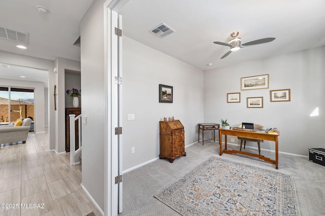 office area with a ceiling fan, visible vents, light carpet, and baseboards