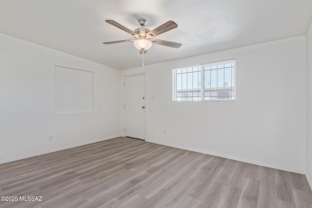 empty room with light wood finished floors, baseboards, and a ceiling fan