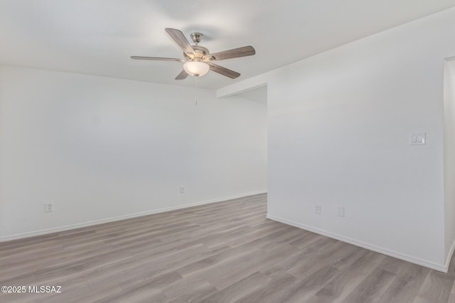 empty room with ceiling fan, light wood-style flooring, and baseboards