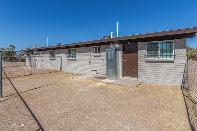 back of house featuring brick siding and fence