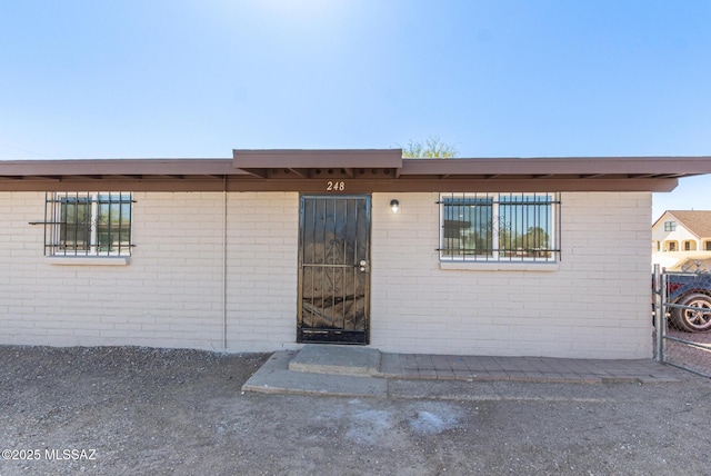 entrance to property featuring brick siding and fence
