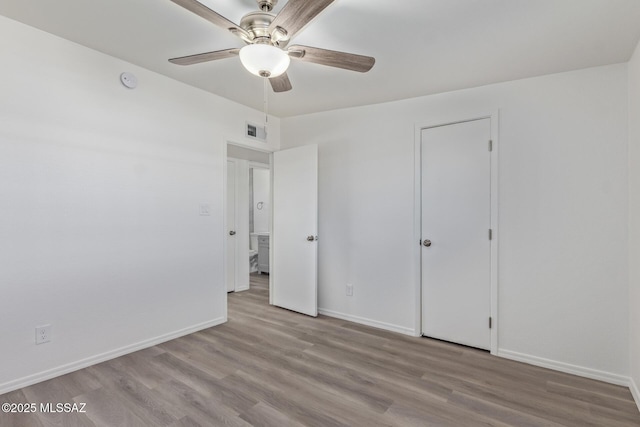 unfurnished bedroom featuring ceiling fan, wood finished floors, visible vents, and baseboards