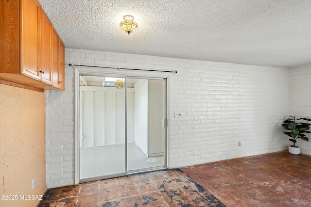 empty room with brick wall and a textured ceiling