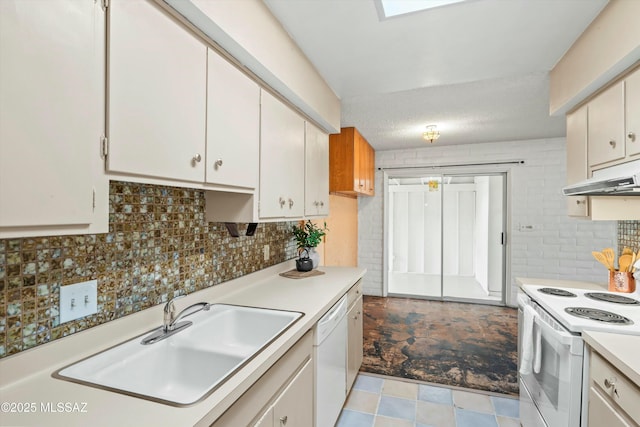 kitchen with light countertops, backsplash, a sink, white appliances, and under cabinet range hood