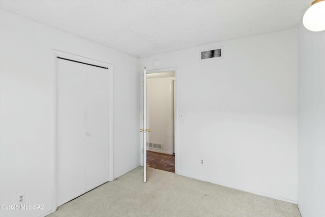 unfurnished bedroom with a closet, carpet, and visible vents