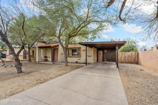 view of front of home featuring a carport, driveway, brick siding, and fence