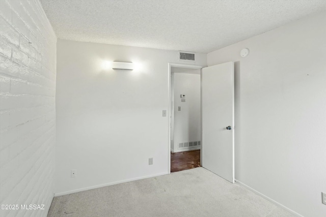 spare room with baseboards, carpet, visible vents, and a textured ceiling