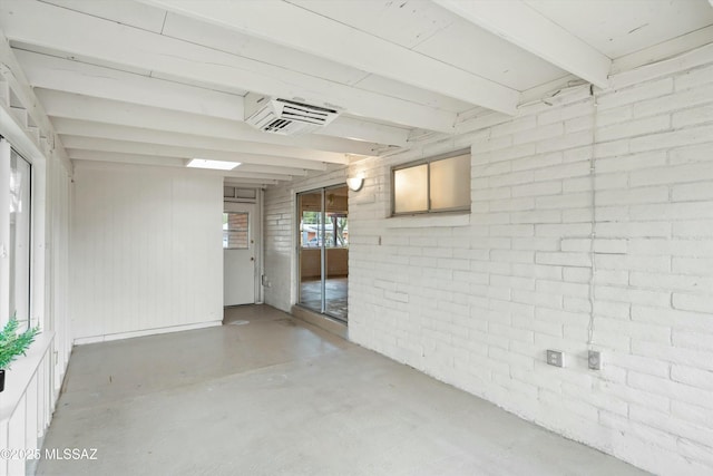 unfurnished room with concrete flooring, beam ceiling, and brick wall