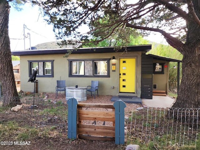 view of front facade featuring entry steps, fence, and stucco siding