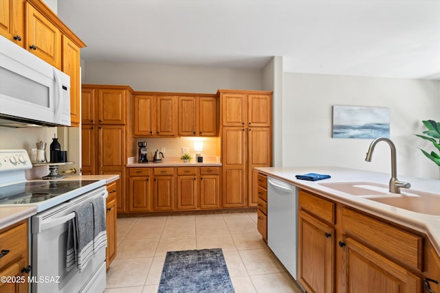 kitchen featuring light countertops, a sink, brown cabinetry, and white appliances