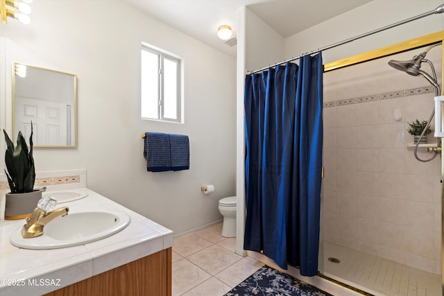 bathroom with a sink, toilet, tile patterned flooring, and tiled shower