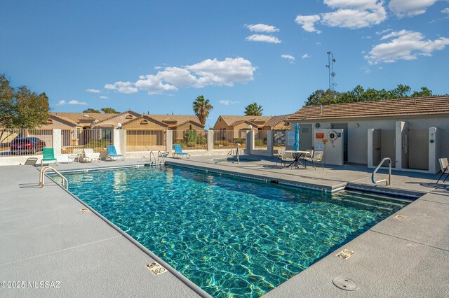 pool with a residential view, fence, and a patio area