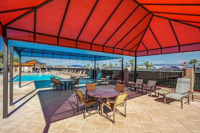 view of patio featuring fence, a gazebo, and a community pool
