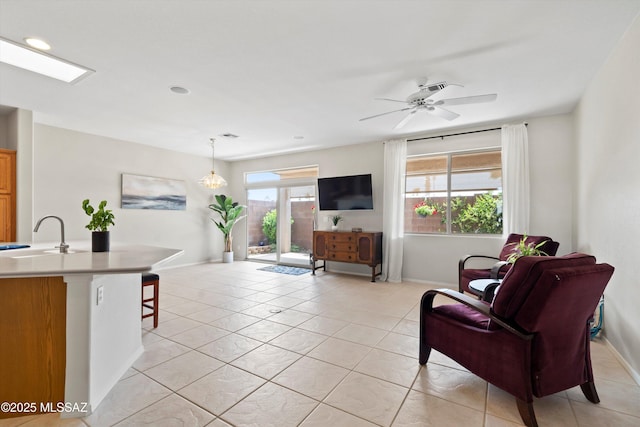 living area with baseboards, a ceiling fan, and light tile patterned floors