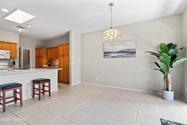 kitchen with light countertops, a skylight, a kitchen breakfast bar, visible vents, and white microwave