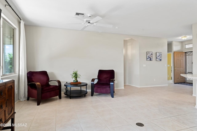 sitting room featuring light tile patterned floors, baseboards, visible vents, arched walkways, and ceiling fan